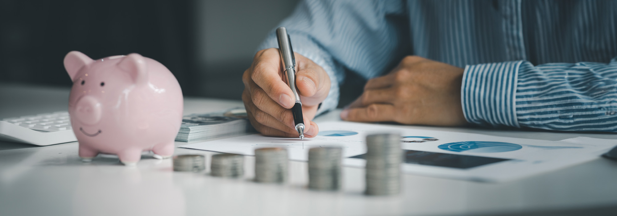 stacks of coins arranged in a row from low to high with man adjusting money projection sheets in background