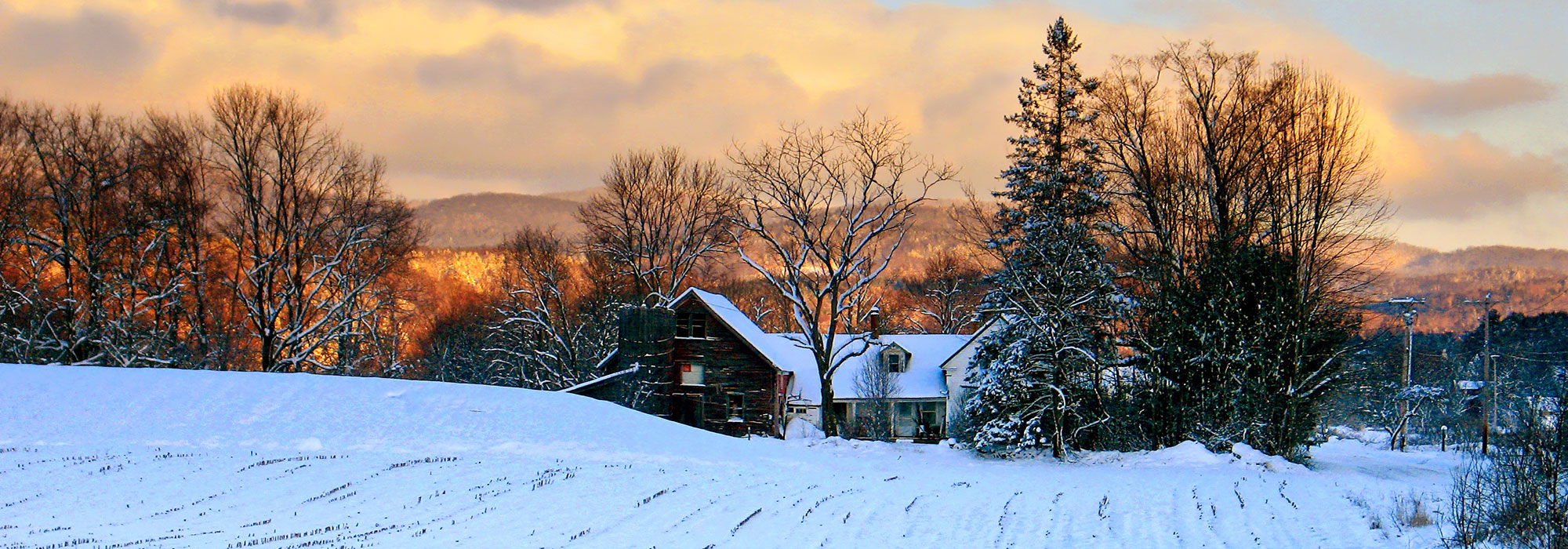 snowy Vermont farm house at sunset in winter