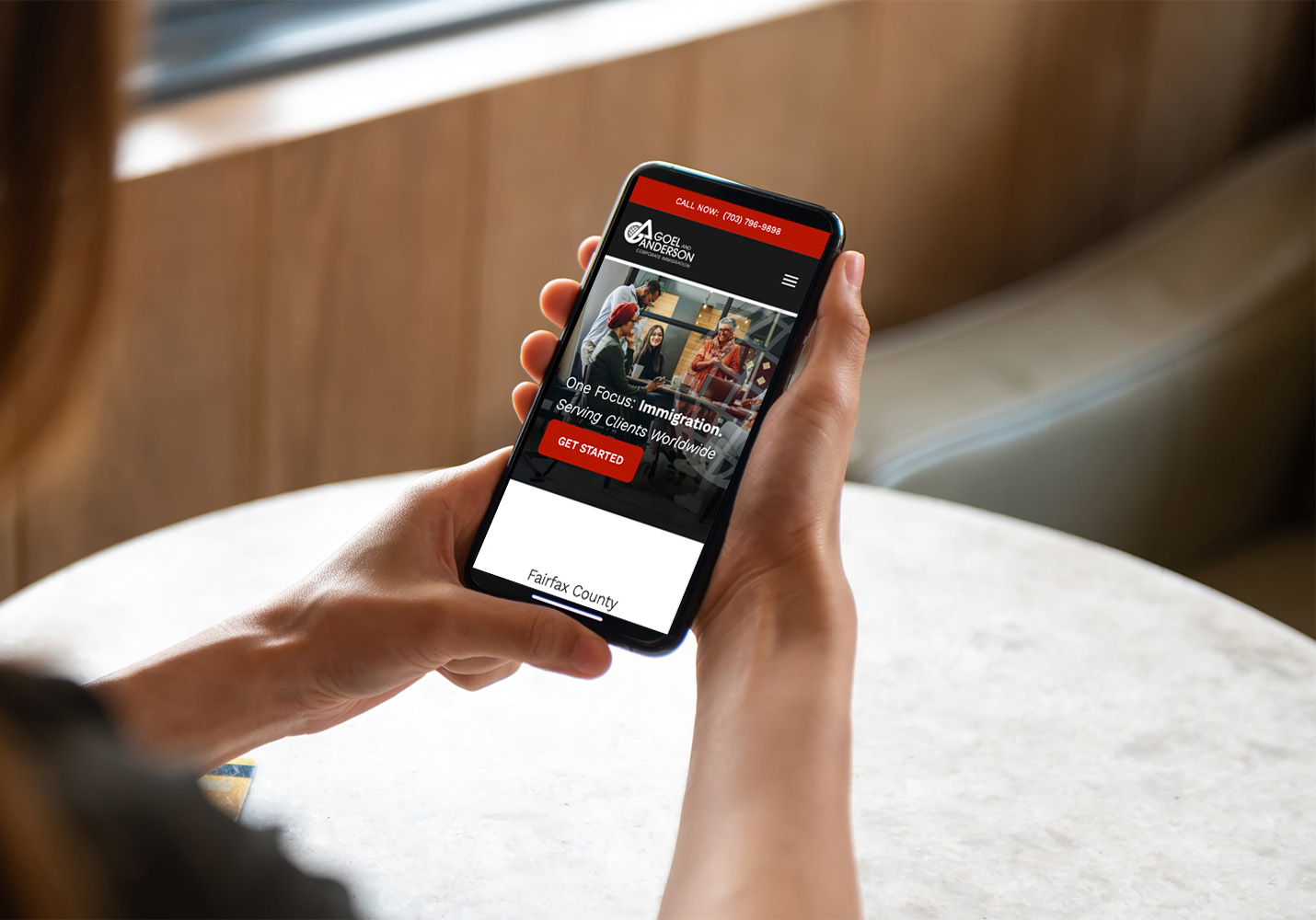 A person holds a smartphone displaying a website for Action Music, featuring images of guitars and the text 