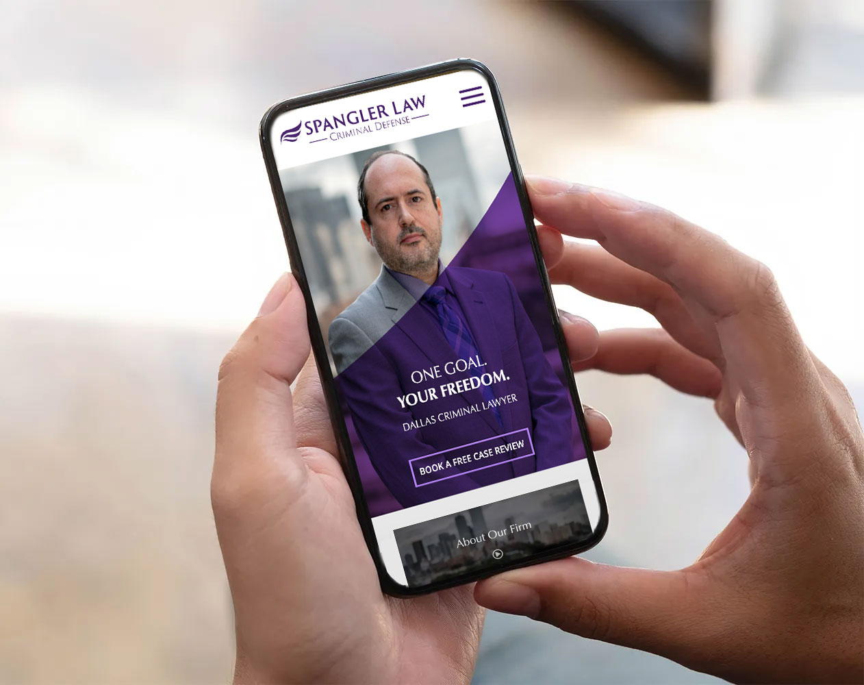 A person holds a smartphone displaying a website for Spangler Law, criminal defense. The screen shows a man in a suit, the text 