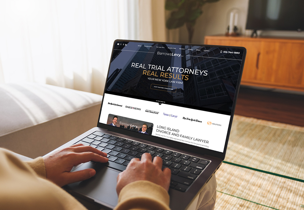 A person types on a laptop displaying the Barrows Levy law firm website, featuring a banner for real trial attorneys, law firm logos, and contact information, in a cozy, sunlit living room.