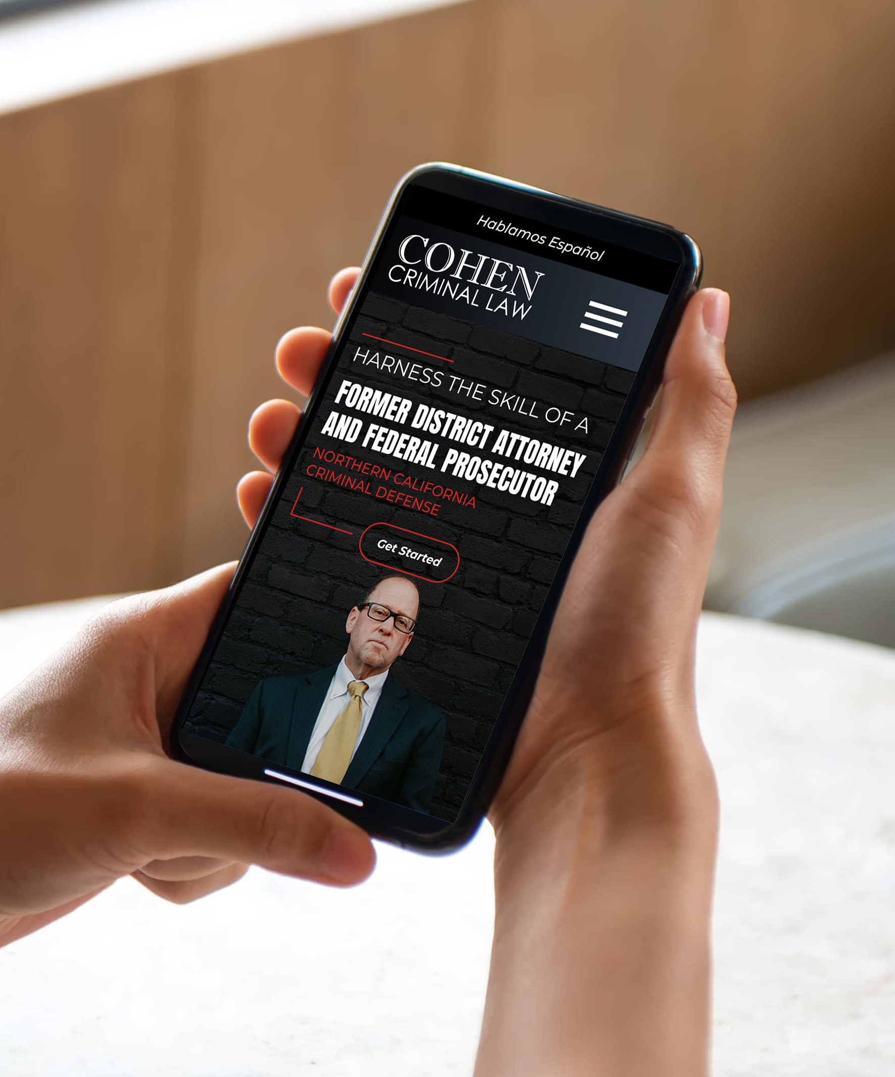 A person holds a smartphone displaying the Cohen Criminal Law website, which features a lawyer's photo, law firm name, and a call-to-action button that says