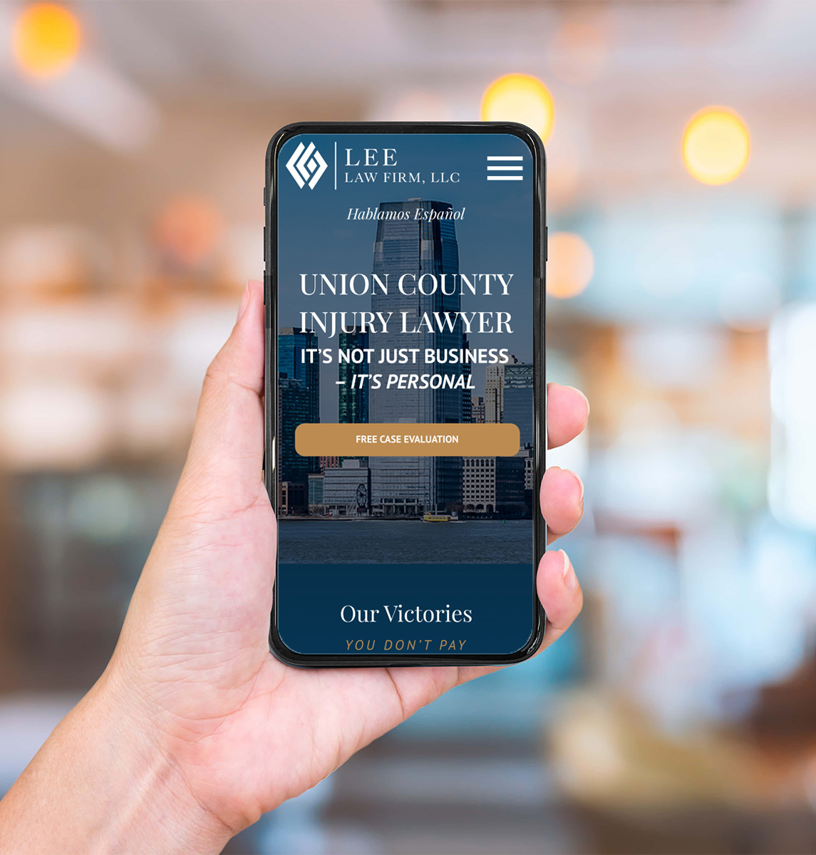 A hand holds a smartphone displaying the Lee Law Firm website, featuring a free case evaluation button and text promoting Union County injury lawyer services. The background is blurred with warm lighting.